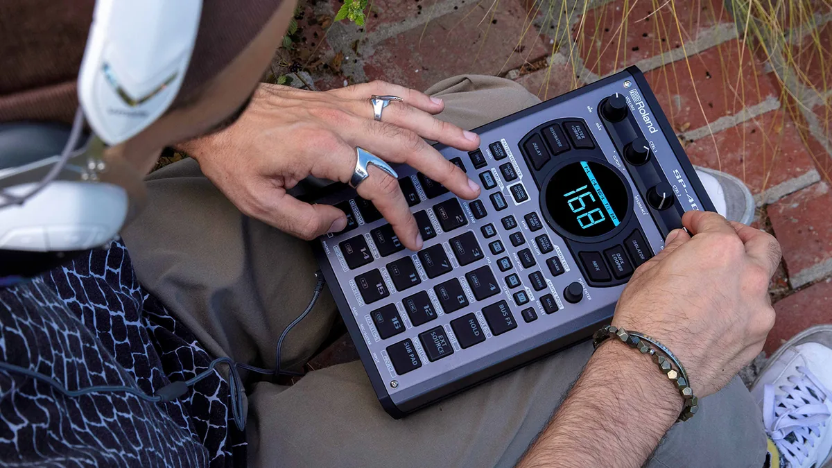 Roland SP-404MKIIを膝の上で操作する手元の写真(画像提供: ローランド)